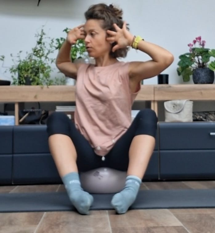 Portrait de Ludivine Brébois, assise sur un petit ballon de Pilates, les mains derrière la tête